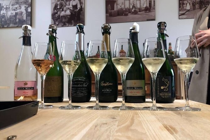 A line of champagne bottles, each with a filled flute, on a tasting table