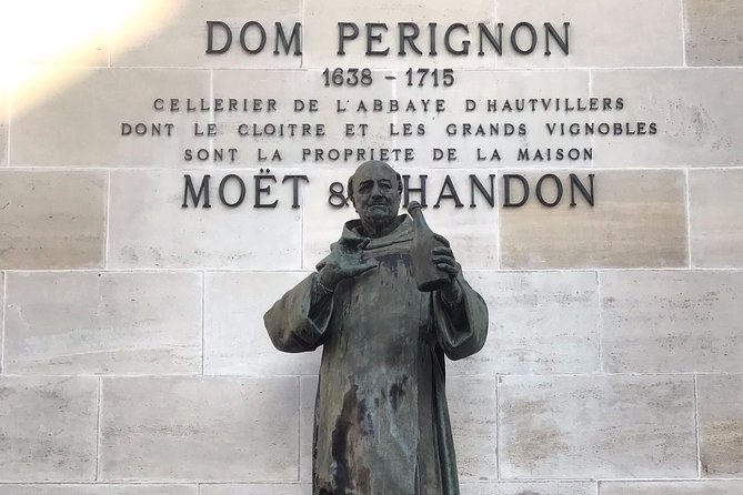The statue of Dom Pérignon before a carved inscription naming him cellar master of the abbey of Hautvillers