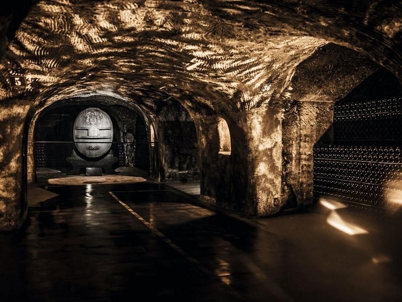A great carved cask at the end of a chalk cellar, its vault lit from below