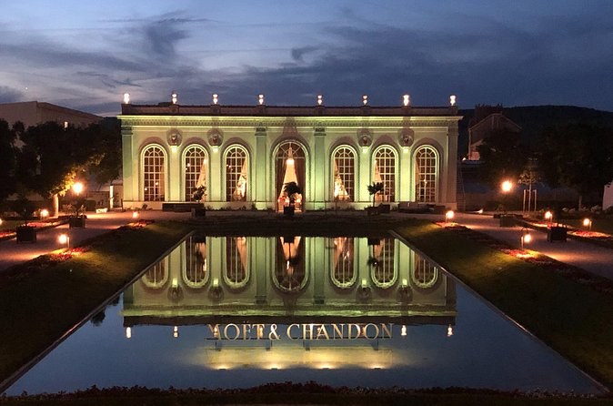 The Moët & Chandon Orangerie lit at night, reflected in a long pool
