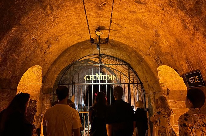 Visitors at the iron gate of the G.H. Mumm cellars under a vaulted ceiling