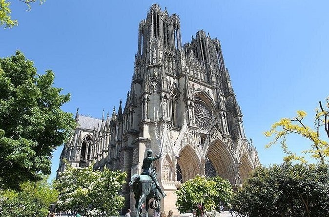 Reims Cathedral seen from the side, an equestrian statue among the trees below