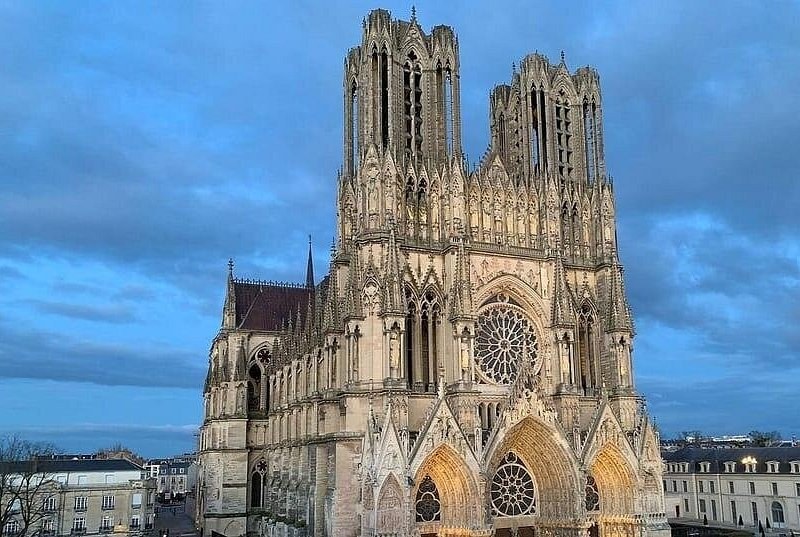 Reims Cathedral's west front and its two towers under a blue evening sky