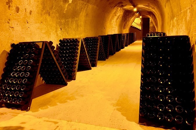 Riddling racks of bottles set out along a lit cellar gallery