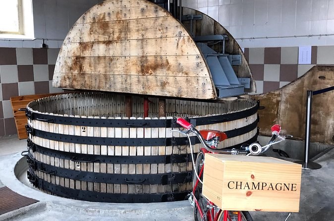 A traditional round wooden press, a wooden Champagne crate beside it