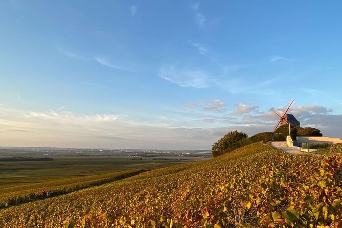 A windmill on a rise above vines turning gold in autumn